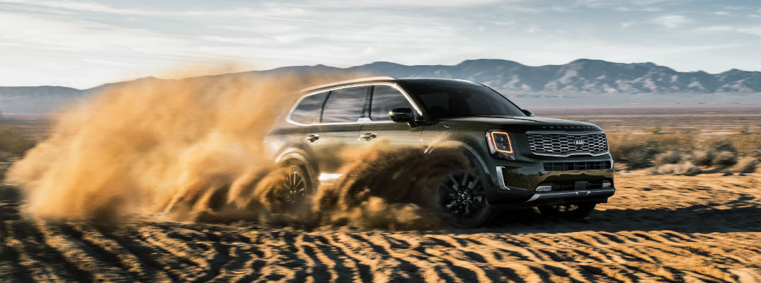 A photo of the 2020 Kia Telluride kicking up sand while driving through the desert.
