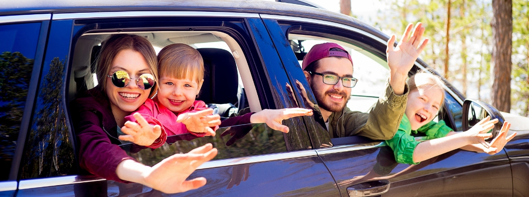 Family of four waving out car window