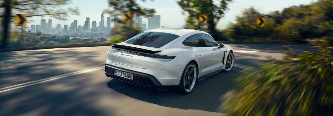 2020 Porsche Taycan driving down road from rear