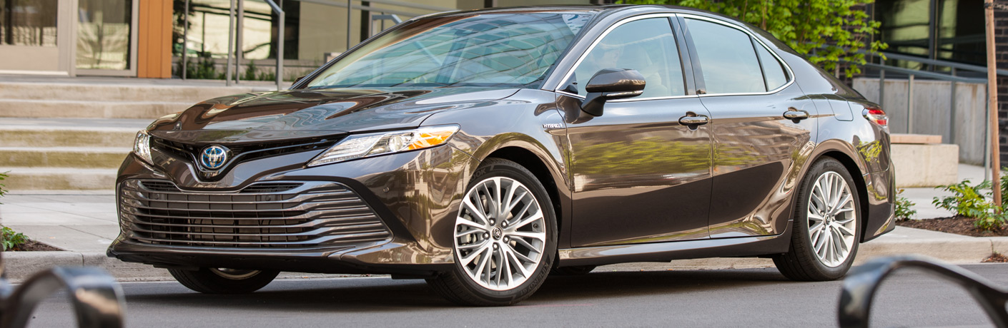 Exterior view of a black 2018 Toyota Camry Hybrid parked curbside in the city