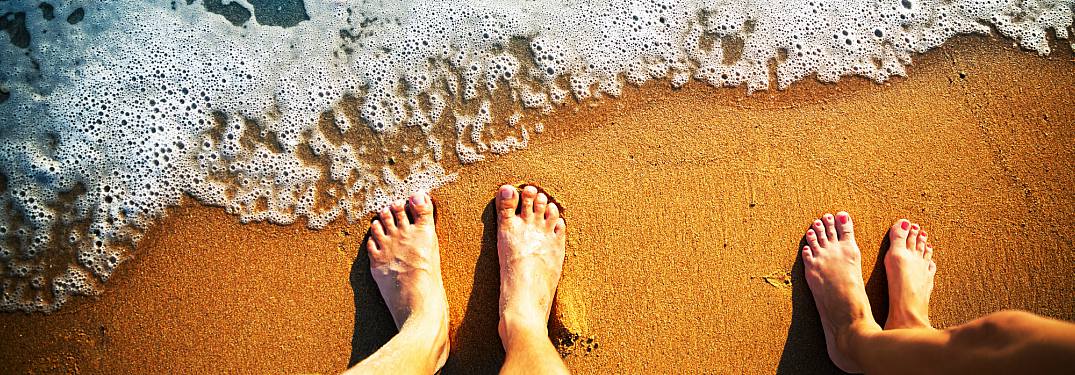 feet on a beach with water