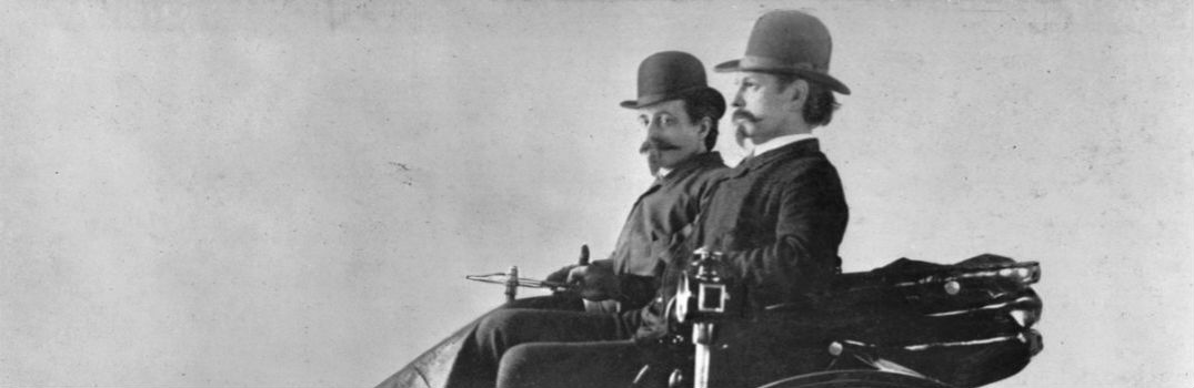 two people riding in the first ever automobile