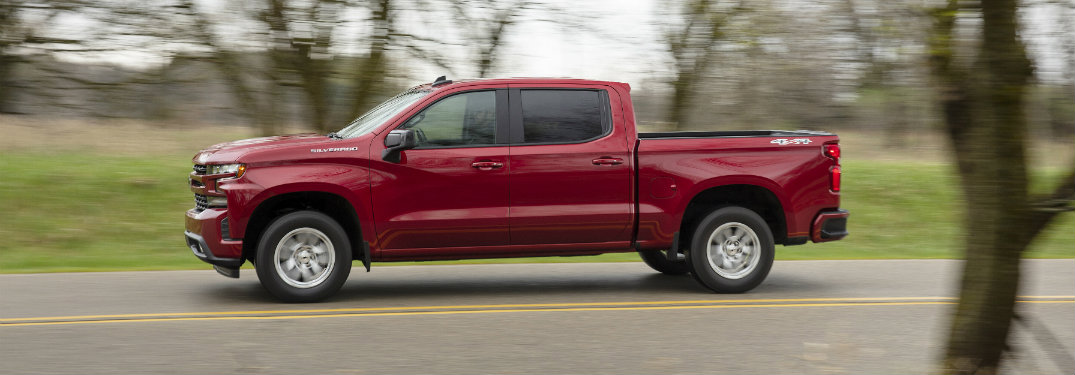 side view of a red 2019 Chevy Silverado driving on the road