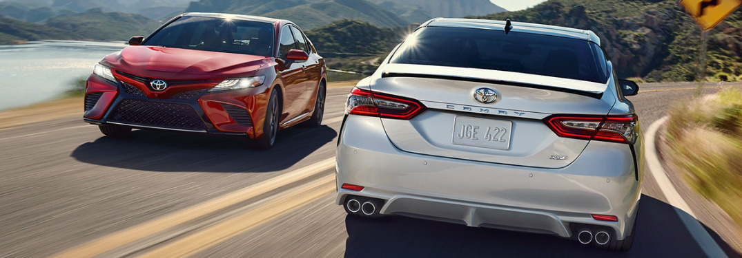 Red and white 2018 Toyota Camry models passing each other on the road