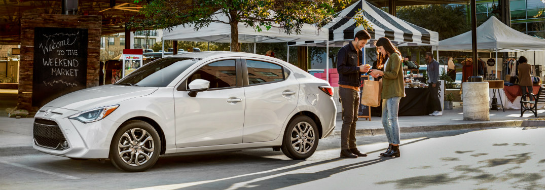 Man and woman standing beside a white 2019 Toyota Yaris