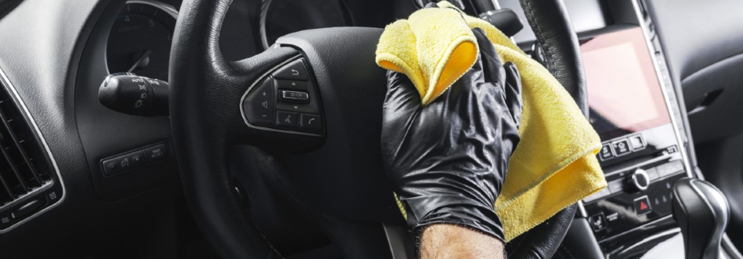 a gloved hand wiping a steering wheel