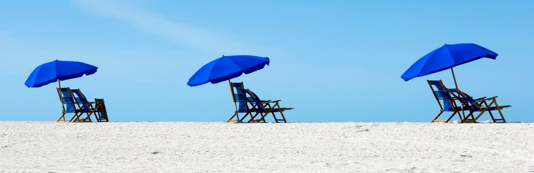 Empty beach chairs with blue umbrellas