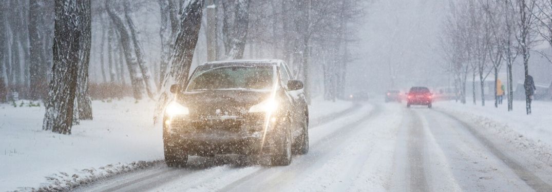 cars driving down snowy road