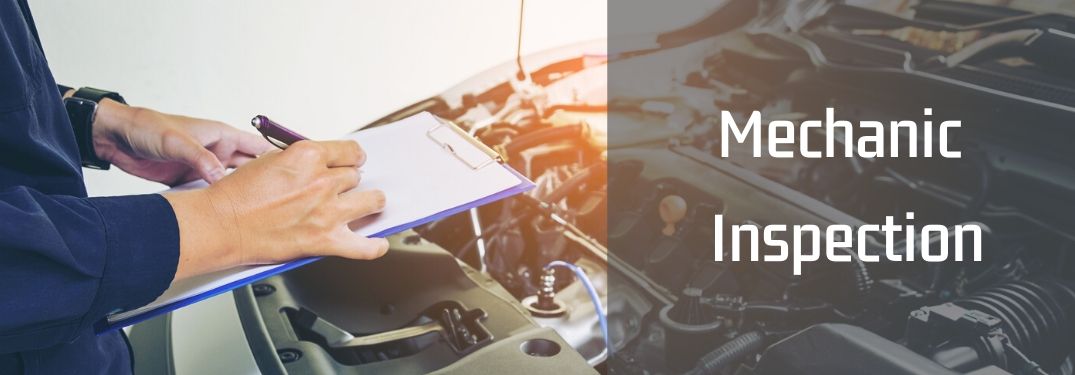 closeup of mechanic hands holding clipboard while inspecting under the hood of a car with the text mechanic inspection written on it