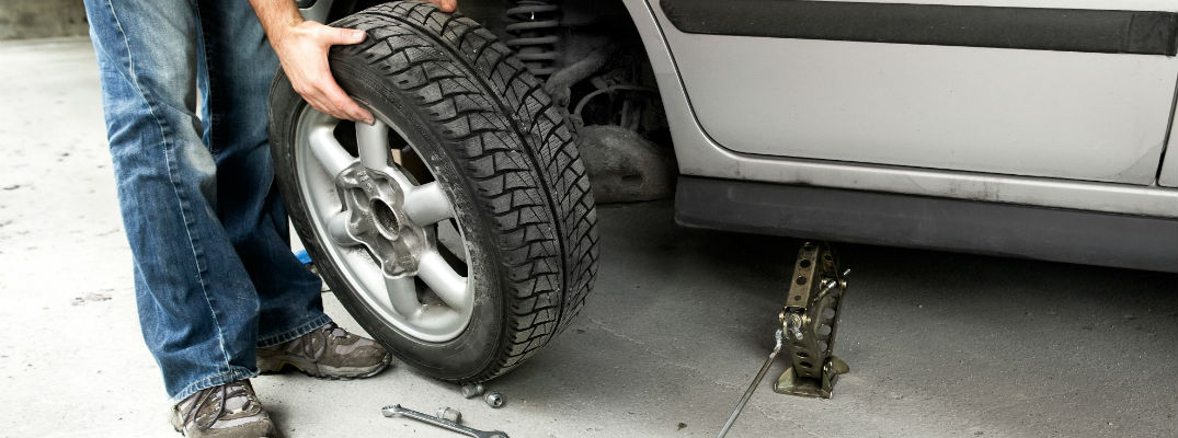 A stock photo of someone changing a tire in a garage.