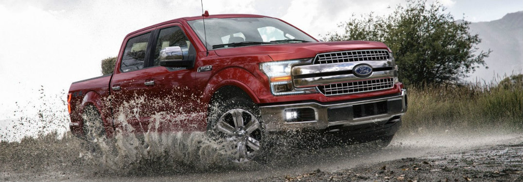 Red 2018 Ford F-150 Raptor driving through muddy water