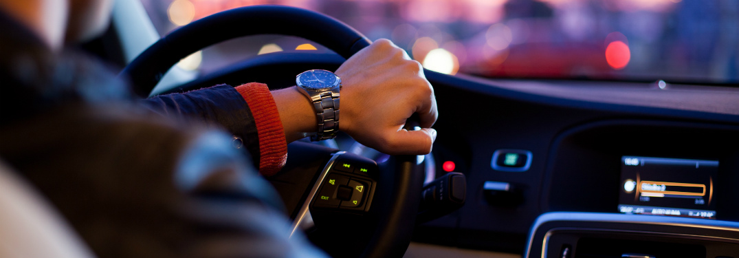 A man's hand on the steering wheel of his car