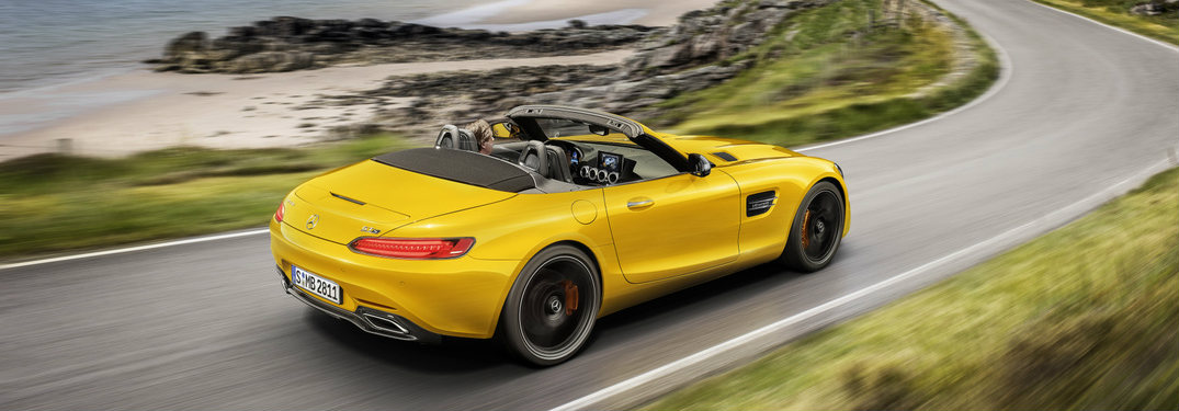 side view of a yellow 2019 Mercedes-AMG® GT S Roadster driving on a curving road