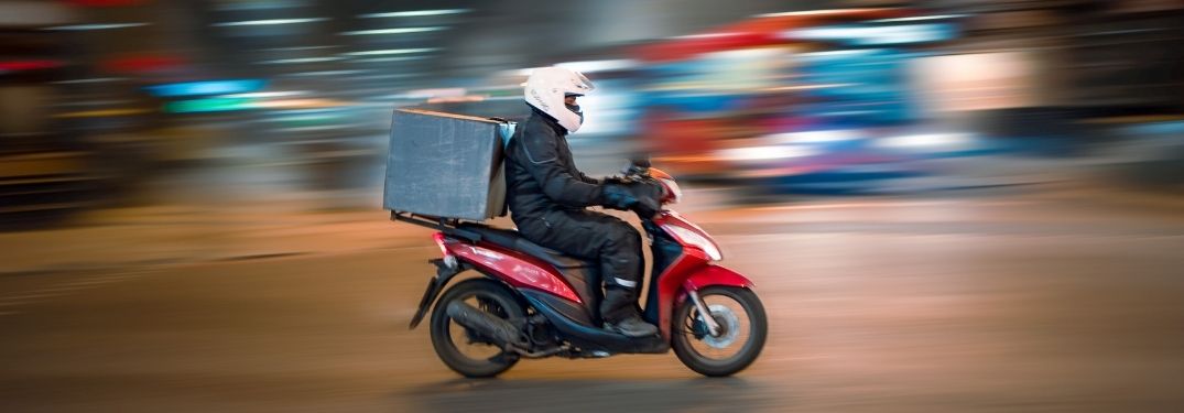 Food delivery agent riding motorcycle on the road