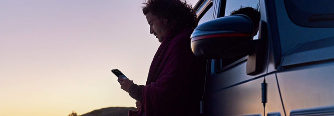 Man using the phone near a vehicle