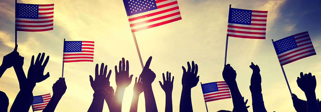 hands waving small American flags at dusk