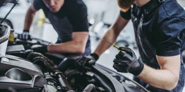 Two auto mechanics working on vehicle