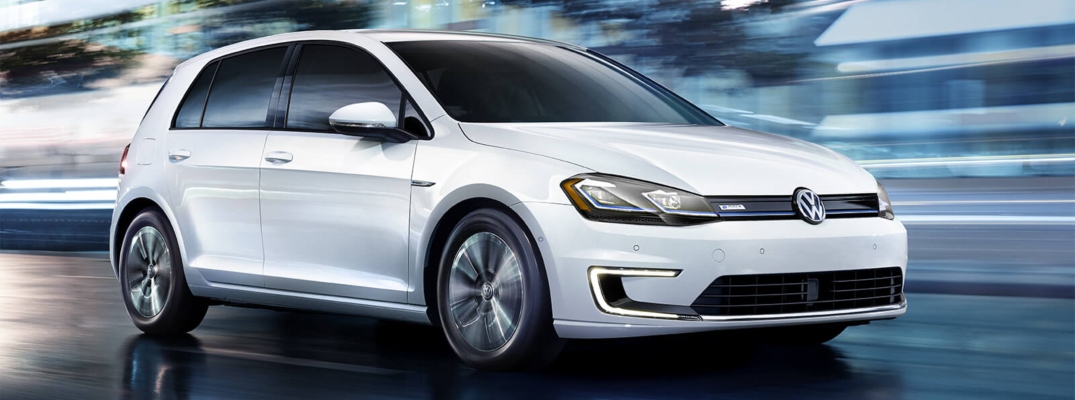 Exterior view of a white 2018 Volkswagen e-Golf driving down a city street