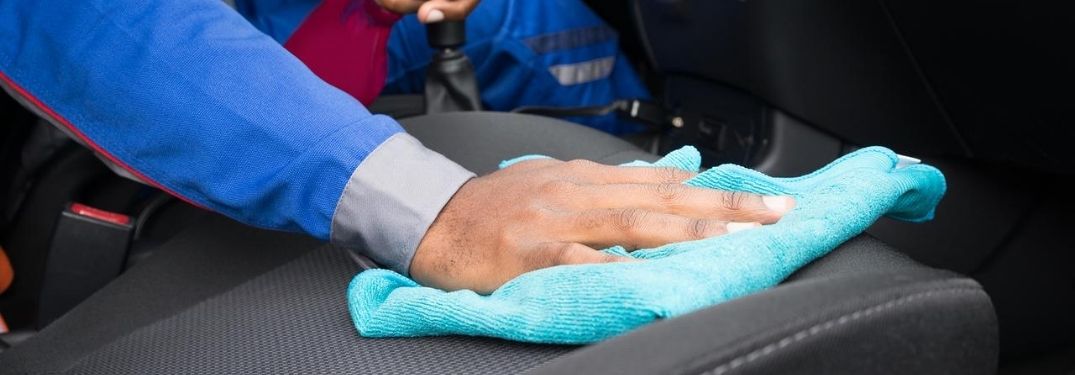 person wiping down car seat with blue cloth