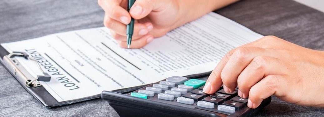 person signing paperwork with calculator