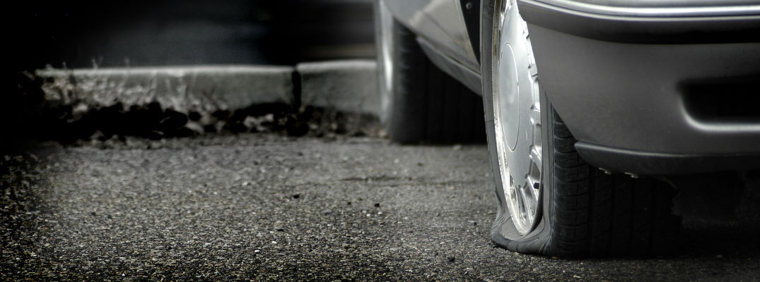 A stock photo of a car with a flat tire in a parking lot.