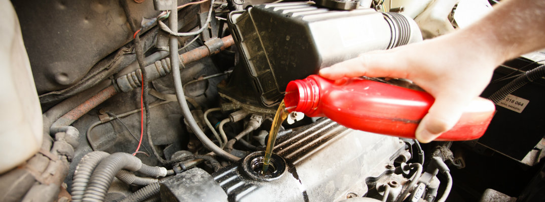 Man pouring engine oil into a car