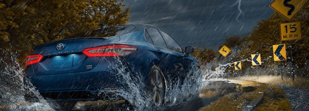 A 2020 Toyota Camry driving down a road during a storm