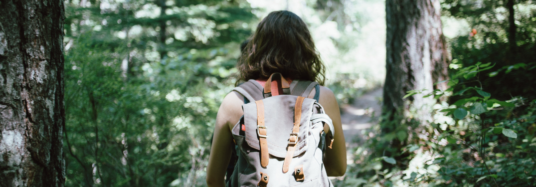 A woman hiking through woods with a backpack