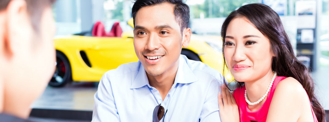 A stock photo of a young couple getting answers at a dealership