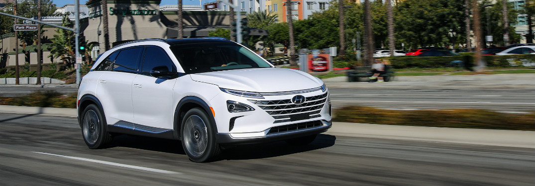 white Hyundai NEXO driving down city street