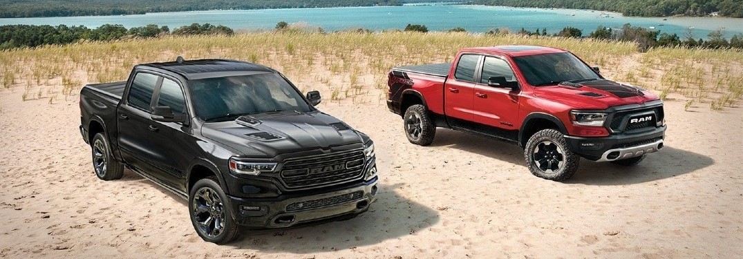 Two 2020 Ram 1500 trucks parked on sandy beach red and black