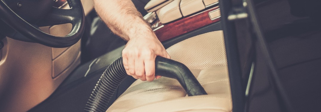 stock photo of hand holding vacuum cleaning leather car seat