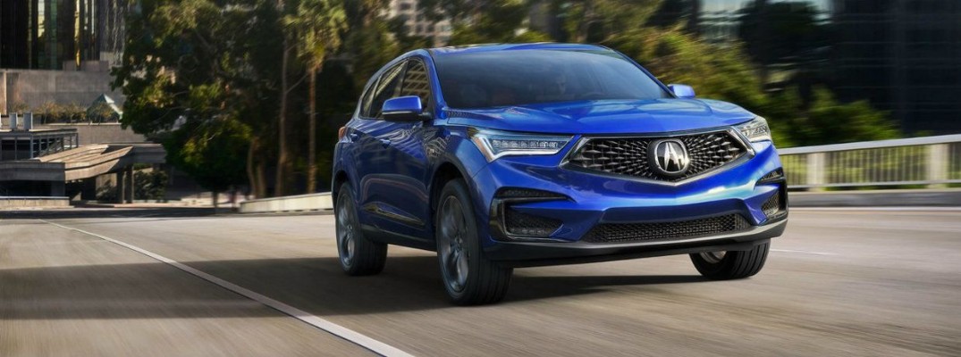 Blue 2019 Acura RDX driving on empty tree-lined road