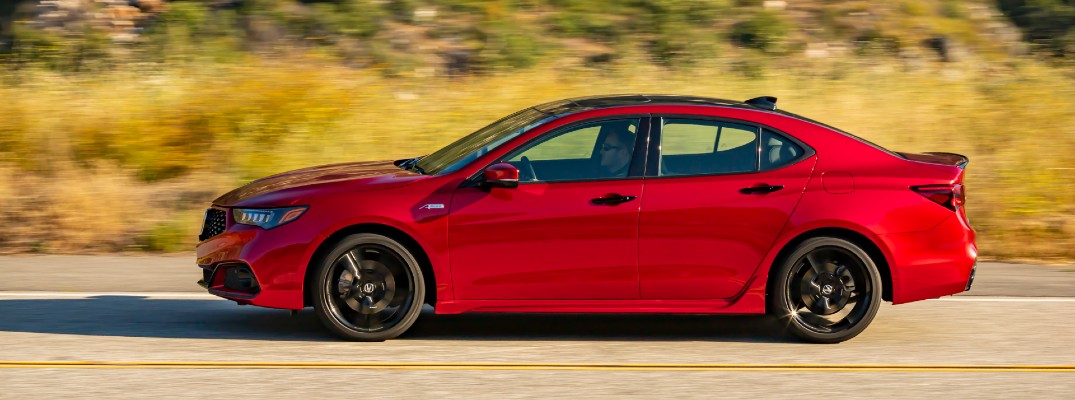 2020 Acura TLX PMC edition red driving to the left on asphalt with dried grasses in background