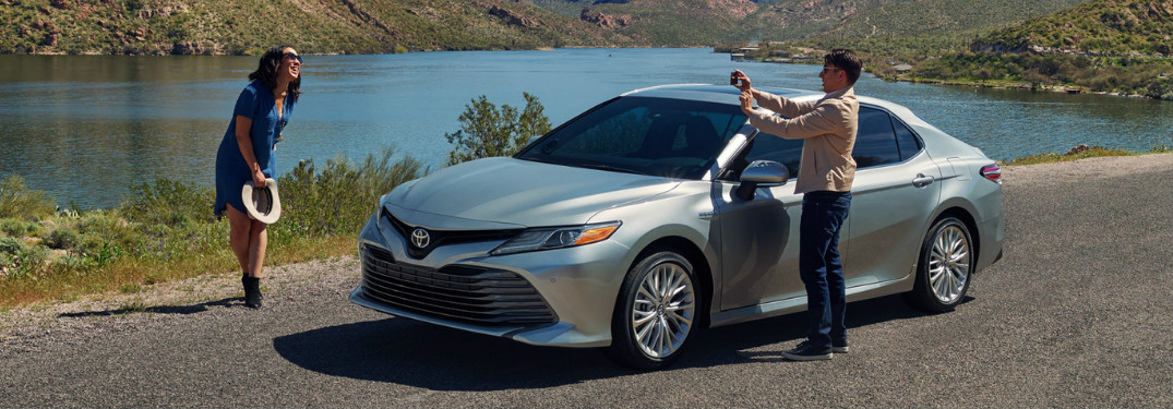 Man Taking a Photo of a Woman Next to a Silver 2018 Toyota Camry