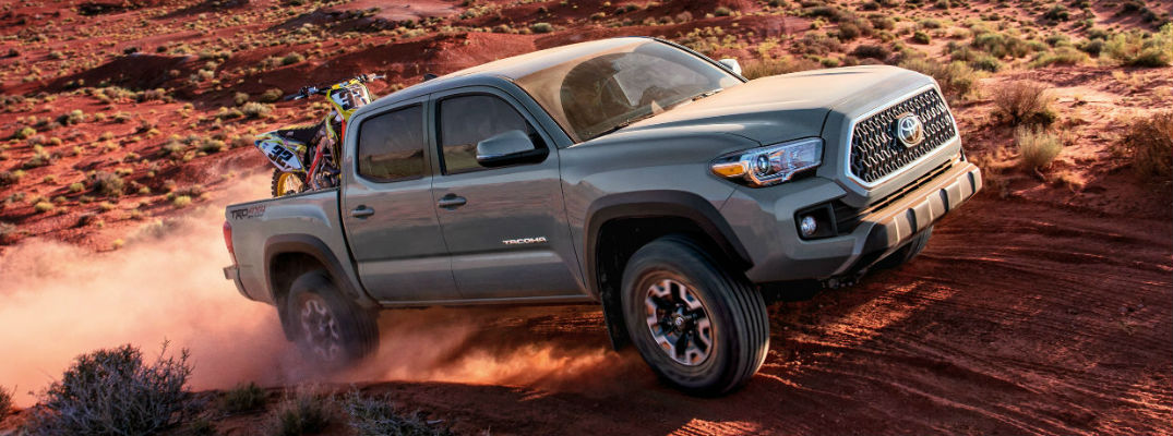 A photo of a Toyota Tacoma crossing the desert with dirt bikes the back