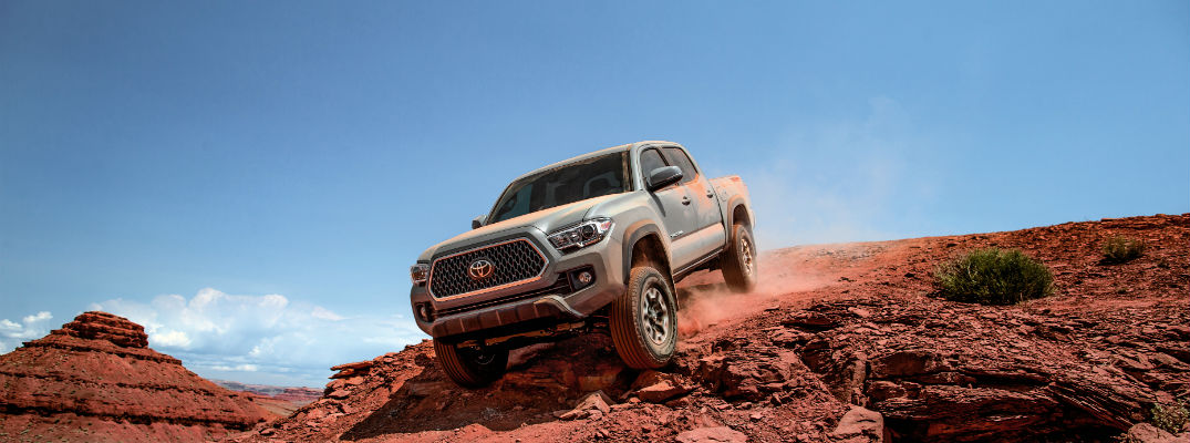 A photo of a 2018 Toyota Tacoma coming over a hill in the desert.