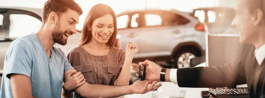 A stock photo of people picking up their keys for a new car.