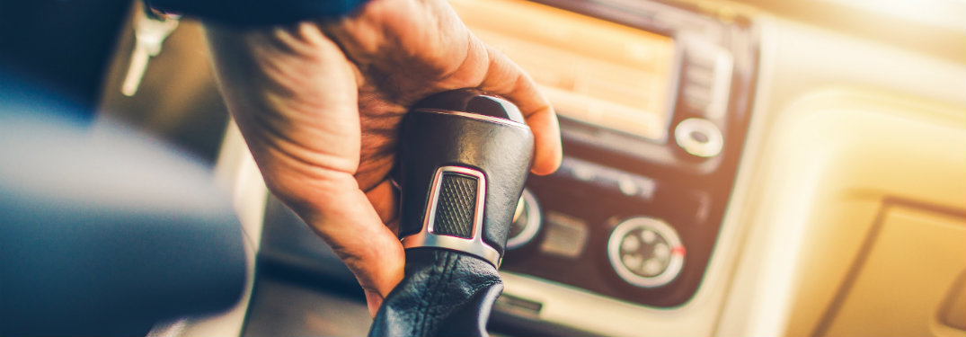 A hand holding a leather-wrapped gear shift knob