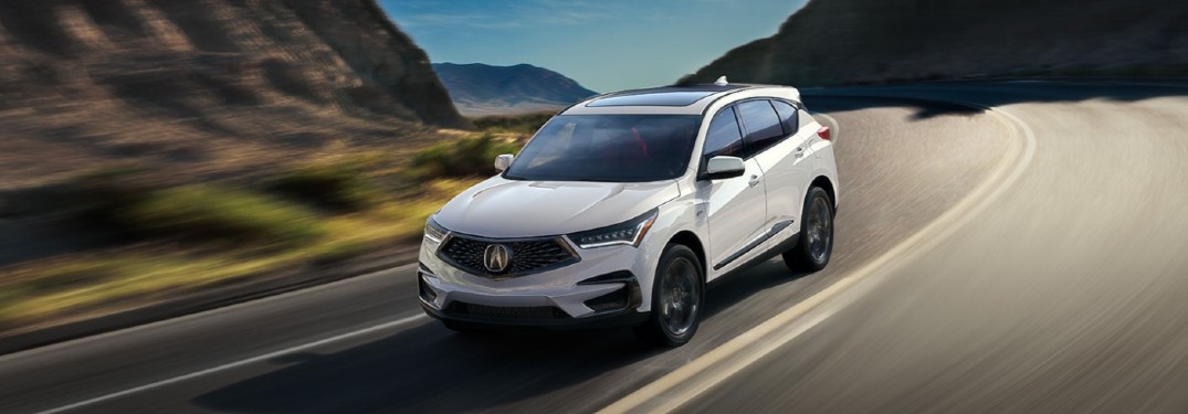 Front driver angle of a white 2021 Acura RDX driving on a road