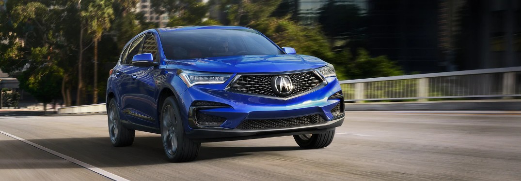 Front passenger angle of a blue 2021 Acura RDX driving on a road