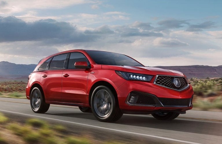 Front passenger angle of a red 2020 Acura MDX A-Spec Package driving on a road