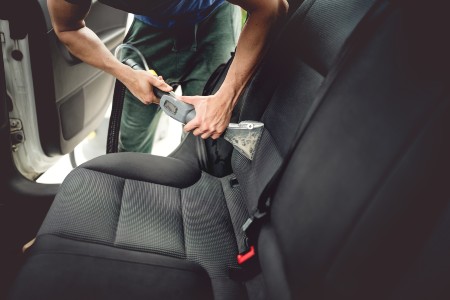 Close up of a person vacuuming car seats