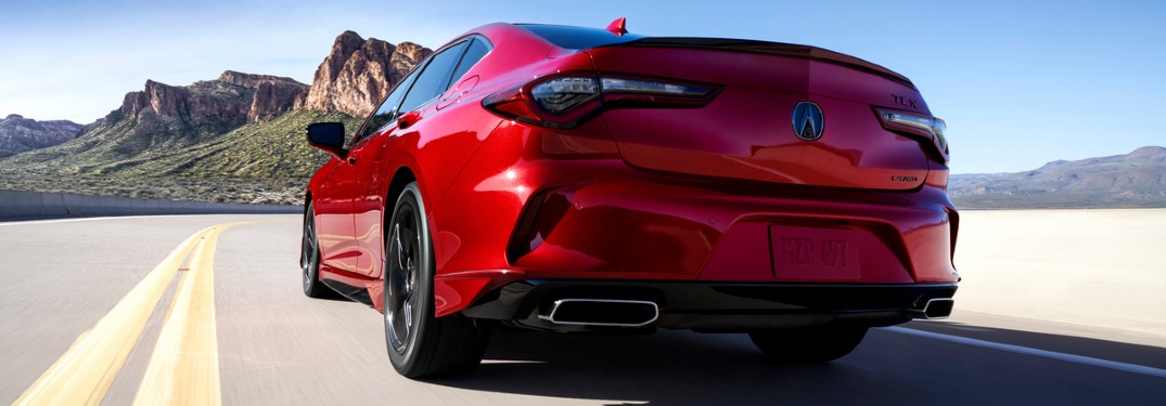 Rear driver angle of a red 2021 Acura TLX driving on a road