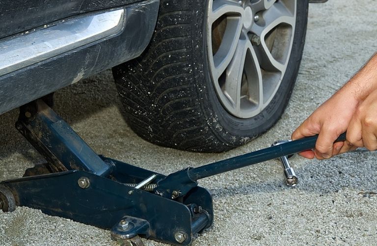 Image of a person using a jack to raise a vehicle
