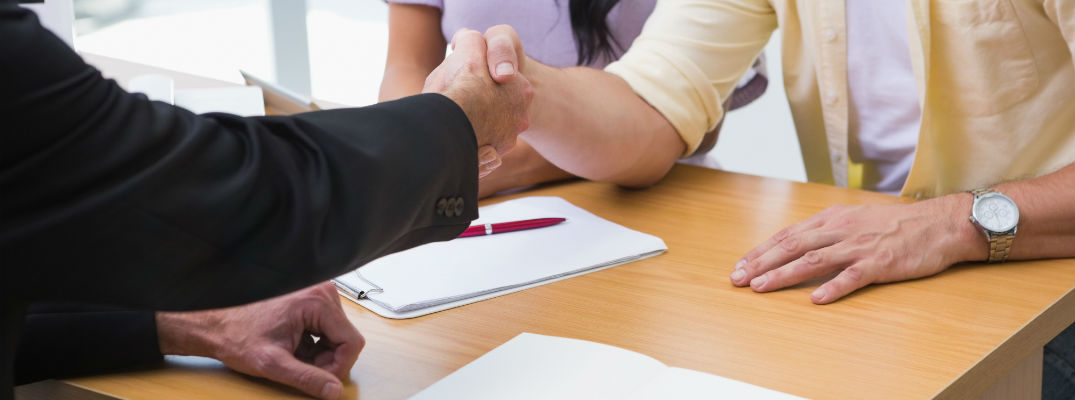 A stock photo of people shaking hands after signing paperwork.