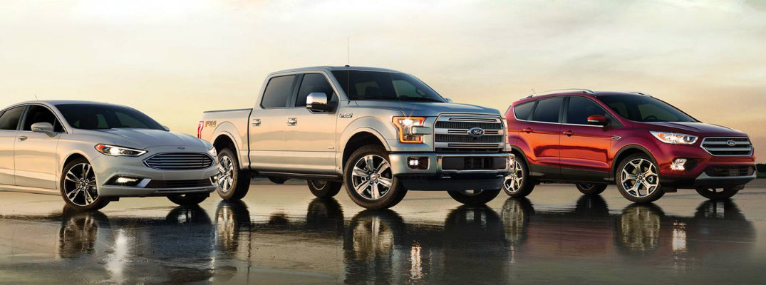 Ford sedan, truck and SUV in a line of three on wet pavement
