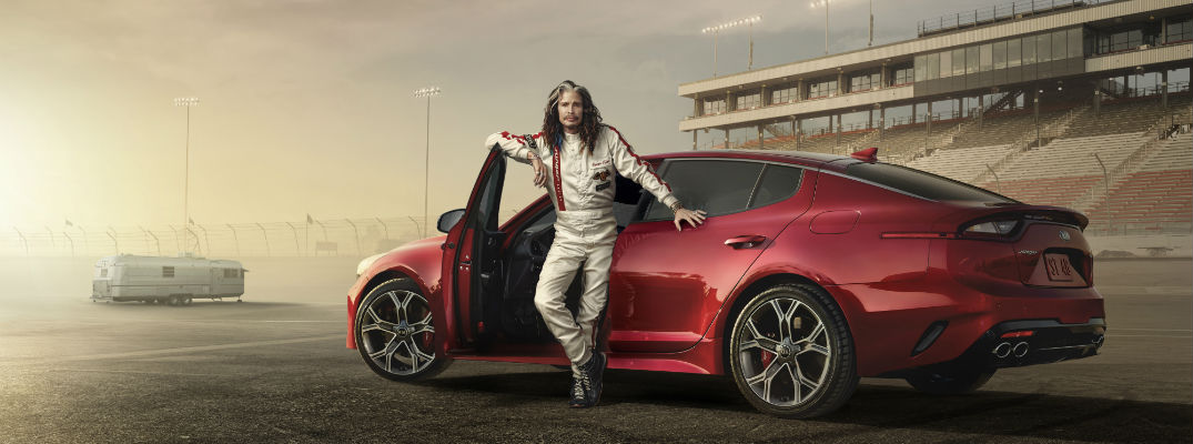 A photo illustration of Steve Tyler from Aerosmith standing in front of a red 2018 Kia Stinger on a race track.