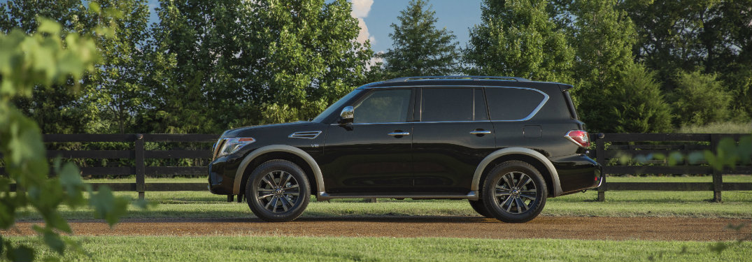 side view of blue 2018 nissan armada on dirt trail surrounded by grass and trees