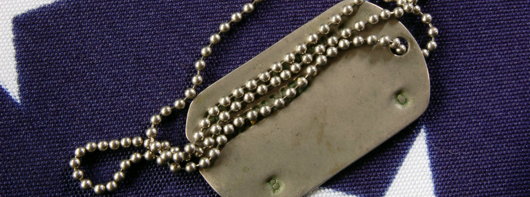 metal dog tag laying atop an folded American flag for a Memorial Day ceremony event